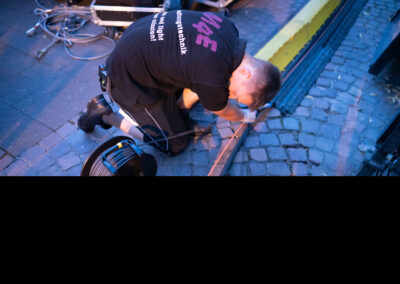 Ein Techniker von M4E Veranstaltungstechnik verlegt Kabel unter einer Kabelbrücke, so dass Zuschauer nicht über die Kabel stolpern und diese auch nicht beschädigt werden.