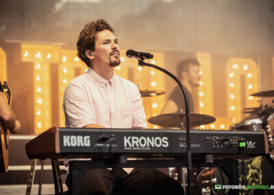 Ein Keyboarder mit einem Korg Kronos auf einer schön ausgeleuchteten Bühne.