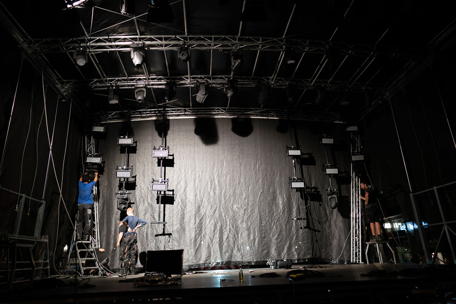 Zwei Bühnentechniker installieren Flutscheinwerfer oder Blinder auf einer Bühne.