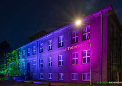 Grün, blau und lila angelcheutete Fassade mit einer Gobo-Message für Vielfalt und Toleranz. M4E Veranstaltungstechnik Referenz Evonik