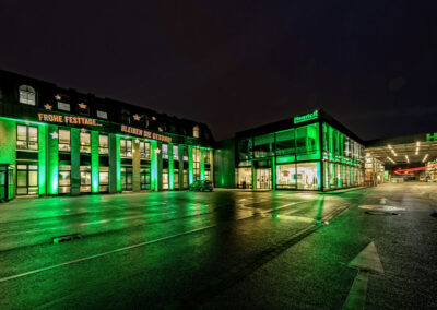 Aussenansicht der am Abend weihnachtlich grün angeleuchteten Fassade des Baustoffhandel Henrich in Siegburg.