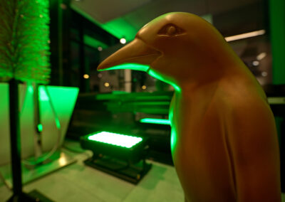 Statue eines goldenen Vogels vor grüner Beleuchtung.