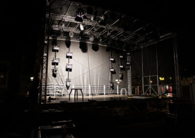 Open-Air Bühne mit Arbeitslicht, auf denen die Installation von Lichttechnik und Tontechnik zu sehen ist.