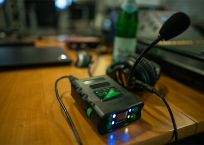 Ein Gerät für das Live Streaming von Video liegt auf einem Tisch, dahinter ein Kopfhörer mit Sprecheinrichtung.