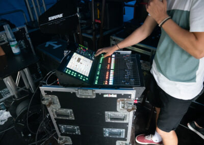 Ein Tontechniker vor einem Monitormischpult, welches auf einer Bühne installiert ist.