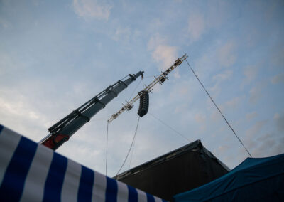 Ein an einem Kran hochgezogenes Rigging an dem ein Line-Array für die Beschallung eines Open Air Festivals befestigt ist. Tontechnik von M4E Veranstaltungstechnik Siegburg.