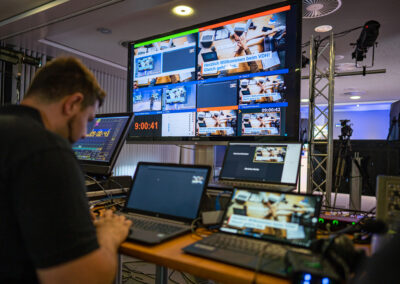 Ein Techniker sitzt vor einem Monitor, um ein Video Streaming zu betreuen. Mit modernster Technik werden Videosbilder live in das Internet übertragen.